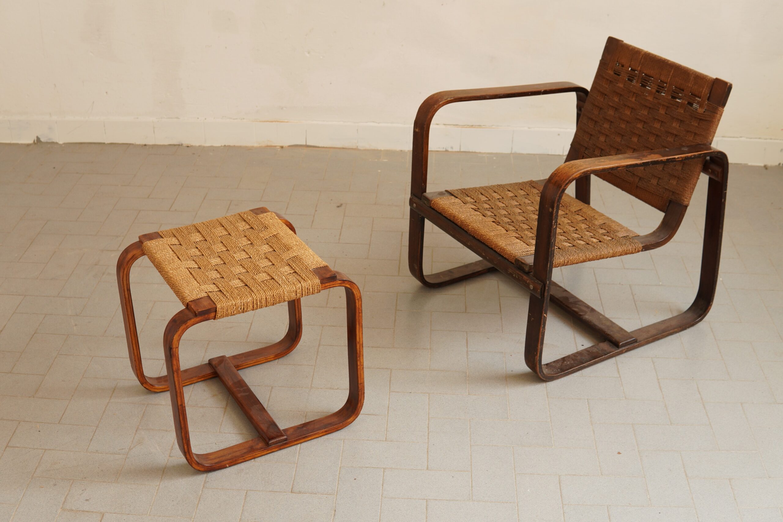Giuseppe Pagano — “Bocconi” Armchair with Matching Footstool, c. 1940 A rare and exceptionally elegant “Bocconi” armchair with its matching footstool, designed by the great Italian Rationalist architect Giuseppe Pagano Pogatschnig. The sculptural structure in curved laminated wood is complemented by finely handwoven natural cord, creating a particularly accomplished balance between architectural rigour and understated comfort. Both pieces retain their beautiful original patina, with the gentle wear and mellow tonal variations that only many decades of honest use can bestow. Far from diminishing the set, these traces of age lend it authenticity, depth and considerable decorative presence. The model was conceived around 1940–42 for the interiors of Milan’s Bocconi University and is associated with the production of Gino Maggioni. It remains one of the most recognisable examples of Italian Rationalist furniture. Born in Parenzo in 1896, Giuseppe Pagano was one of the leading figures of Italian Rationalism: architect, designer, photographer and influential editor of Casabella. A committed anti-Fascist, he was arrested and deported, dying at Mauthausen in 1945. His brief yet remarkable career left an enduring mark upon twentieth-century Italian architecture and design. #GiuseppePagano #ItalianRationalism #BocconiChair #CollectibleDesign #OriginalPatina